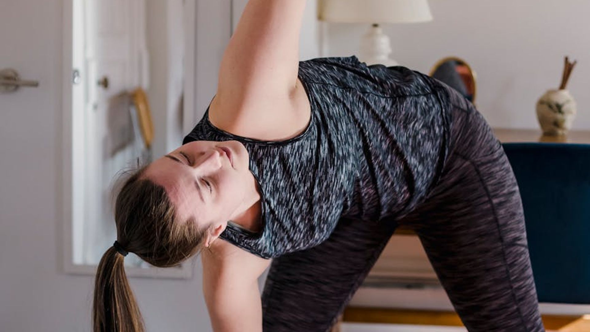 Person practicing yoga in a dark room with warm lighting accents